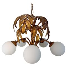 a chandelier with five lights hanging from it's center and leaves on the bottom