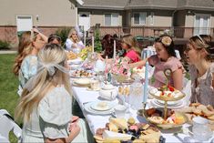 a group of women sitting around a table covered in food