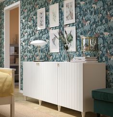 a room with blue and green wallpaper, white furniture and pictures on the wall