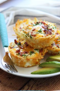 two small quiches on a white plate with avocado and blue utensils