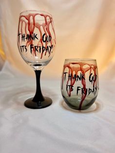 two wine glasses that have been painted with words and blood on the glass, one is saying thank god it's friday