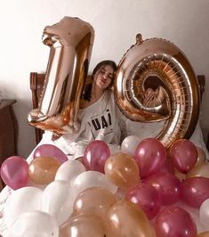 a woman sitting on a bed with balloons in front of her and the number ten