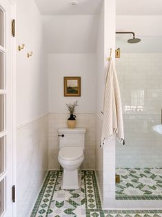 a white toilet sitting in a bathroom next to a walk in shower and tiled floor