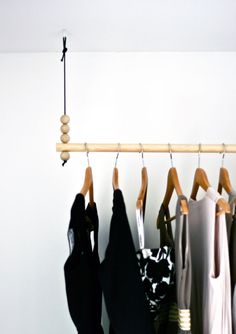 clothes hanging on a wooden rail in front of a white wall