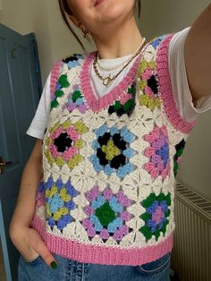 a woman is taking a selfie with her cell phone while wearing a crocheted vest