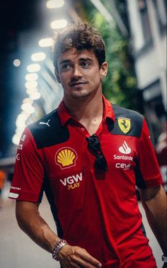 a man wearing a red shirt and black tie standing in the middle of a street