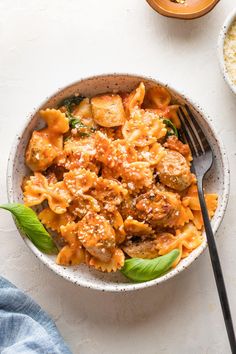 a bowl filled with pasta and meat on top of a white table next to some rice