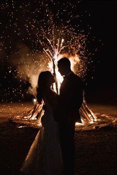 a bride and groom standing in front of fireworks