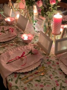 the table is set with pink roses and candles