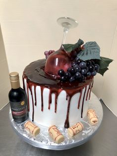 a cake with chocolate icing and fruit on top next to a bottle of wine