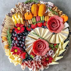 a platter filled with cheeses, fruits and flowers on top of a table