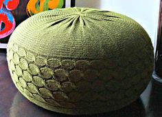 a green knitted bean bag sitting on top of a wooden table next to pictures