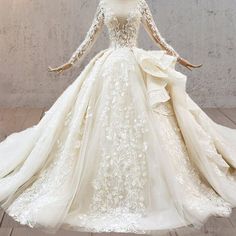 a white wedding dress with long sleeves and flowers on the skirt is displayed in front of a