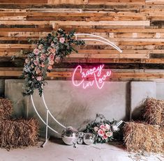 a neon sign that says create surrounded by hay and flowers