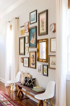 a room with pictures on the wall, and a bench in front of some chairs