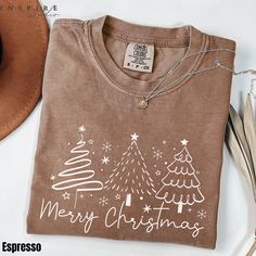 The Comfort Colors® Merry Christmas Winter Tree T-shirt features a minimalistic and elegant design with three unique Christmas trees, accompanied by a "Merry Christmas" message in a modern script. This festive and stylish holiday shirt is perfect for celebrating the Christmas season with a subtle and cozy winter feel. It makes a great gift for her or a holiday wardrobe essential for any festive gathering. Browse our collection and order your favorite t-shirt; 1- Choose your style, size and color Trendy Christmas Shirts, Merry Christmas Message, Christmas Message, Merry Christmas Gift, Cute Christmas Shirts, Winter Tree, Unique Christmas Trees, Holiday Apparel, Merry Christmas Gifts