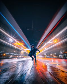 a man is skateboarding down the street at night with bright lights in the background