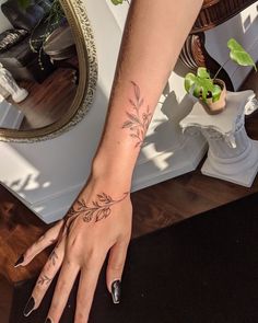 a woman's hand with a flower tattoo on her left wrist and right arm