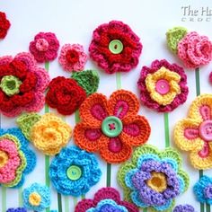 crocheted flowers are arranged on a striped tablecloth with buttons in the center