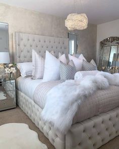 a bed with white fur on it in a bedroom next to a dresser and mirror