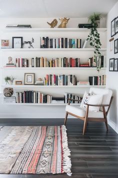 a white chair sitting in front of a book shelf filled with books