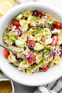 a white bowl filled with pasta salad on top of a blue and white striped towel