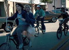 three people riding bikes down the street with cars in the backgrouund and one woman on her bike