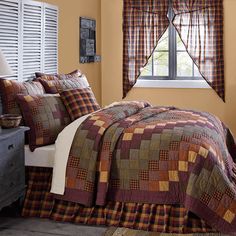 a bed in a room with a plaid comforter and pillows on top of it