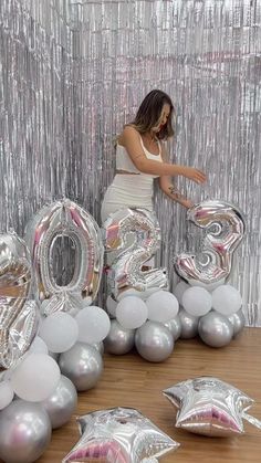 a woman standing in front of balloons that spell out the number 20