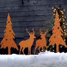 three metal deer standing next to each other in the snow