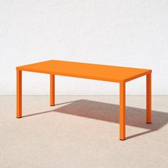 an orange table sitting in front of a white wall