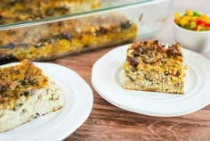 two white plates with food on them next to a casserole dish and salad