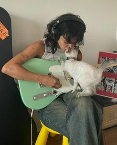 a person sitting on a chair with a guitar and a small white cat in their lap