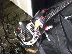 an electric bass guitar sitting on top of a black case next to some cords and wires