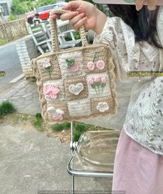 a woman is holding a crocheted purse with flowers on the front and sides