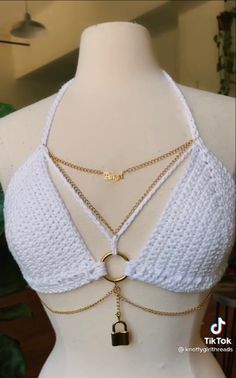 a mannequin wearing a white top with gold chains and a lock on it