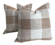 two brown and white checkered pillows sitting next to each other on a white background