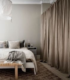 a bed sitting next to a window covered in curtains