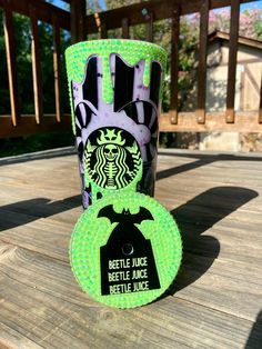 a starbucks cup sitting on top of a wooden table next to a green frisbee