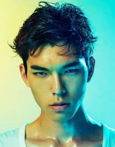 a young man with dark hair and no shirt on posing for a photo in front of a blue background