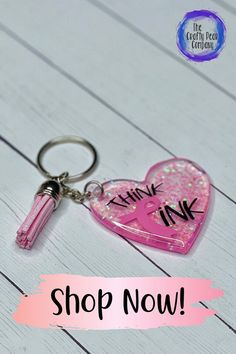 a pink heart shaped keychain with the words think ink on it and a pen sticking out of it