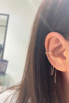 a close up of a person's ear wearing gold earrings