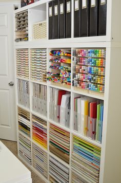 a white bookcase filled with lots of books next to a wall full of folders