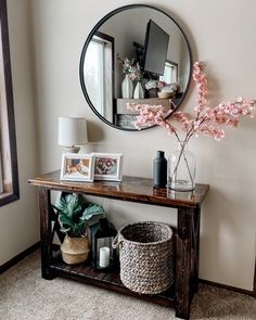 there is a mirror on the wall next to a shelf with pictures and plants in it