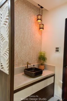 a bathroom sink sitting under a light next to a plant on top of a counter