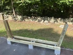 a wooden bench sitting on top of a parking lot next to a stone retaining wall