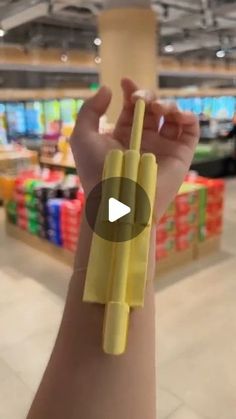 a person holding up a yellow object in the middle of a shopping center with other items behind them