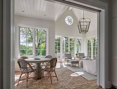 a dining room with brick flooring and white walls on the inside wall is an open door leading to a covered patio area