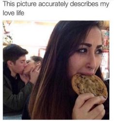 a woman is eating a cookie while sitting at a table with other people in the background