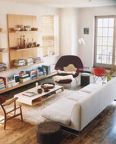 a living room filled with lots of furniture and bookshelves next to a sliding glass door